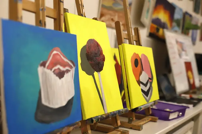 Finished canvas paintings lined up on easels after a painting session