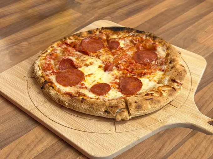 A pepperoni pizza on a wooden peel in the Pictura café kitchen